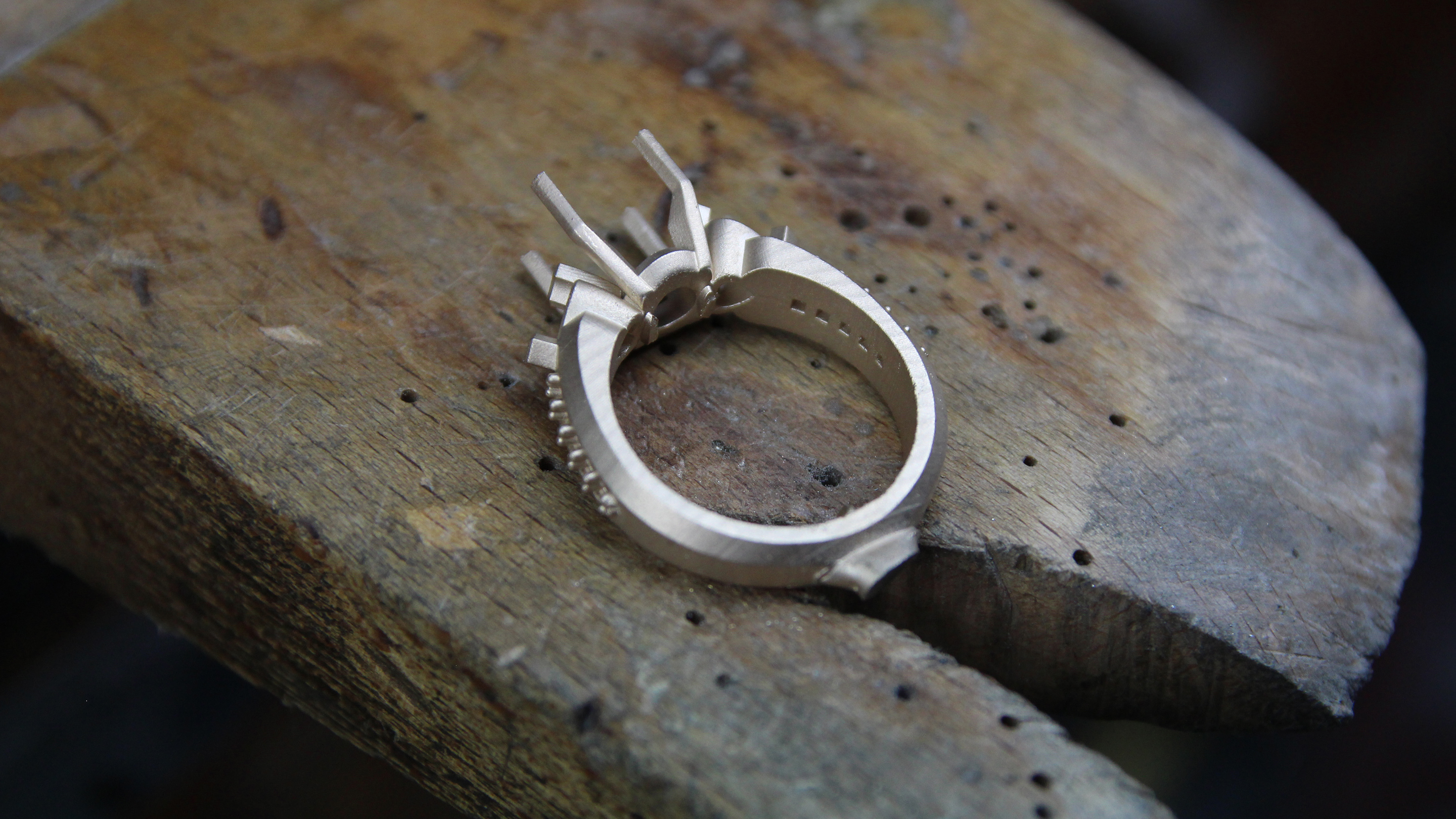 Raw cast ring with casting sprues still attached, on a black ground